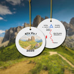 Alta Via 1 ceramic ornament with watercolor landscape shown front and back in front of trail landscape.