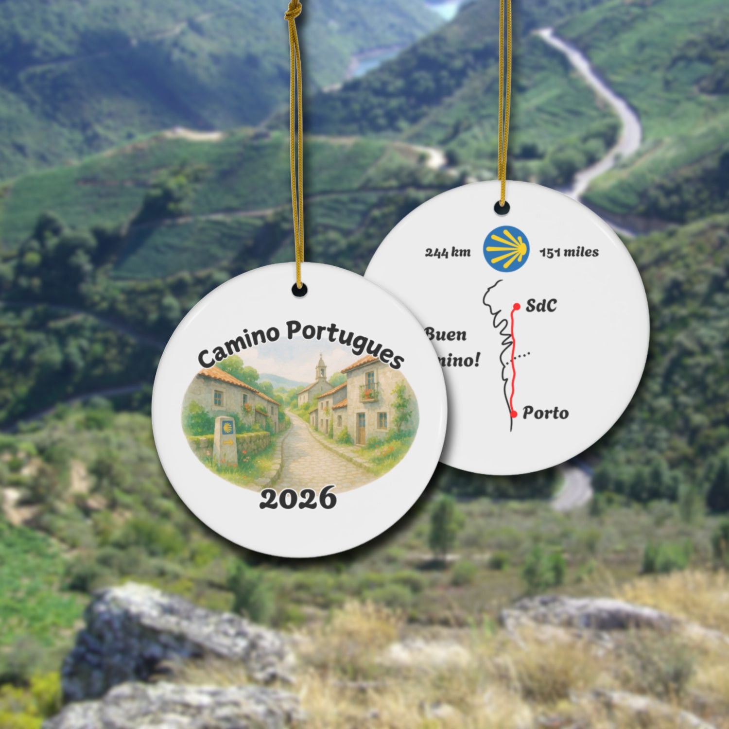Camino Portugues ceramic ornament with watercolor landscape shown front and back in front of trail landscape.
