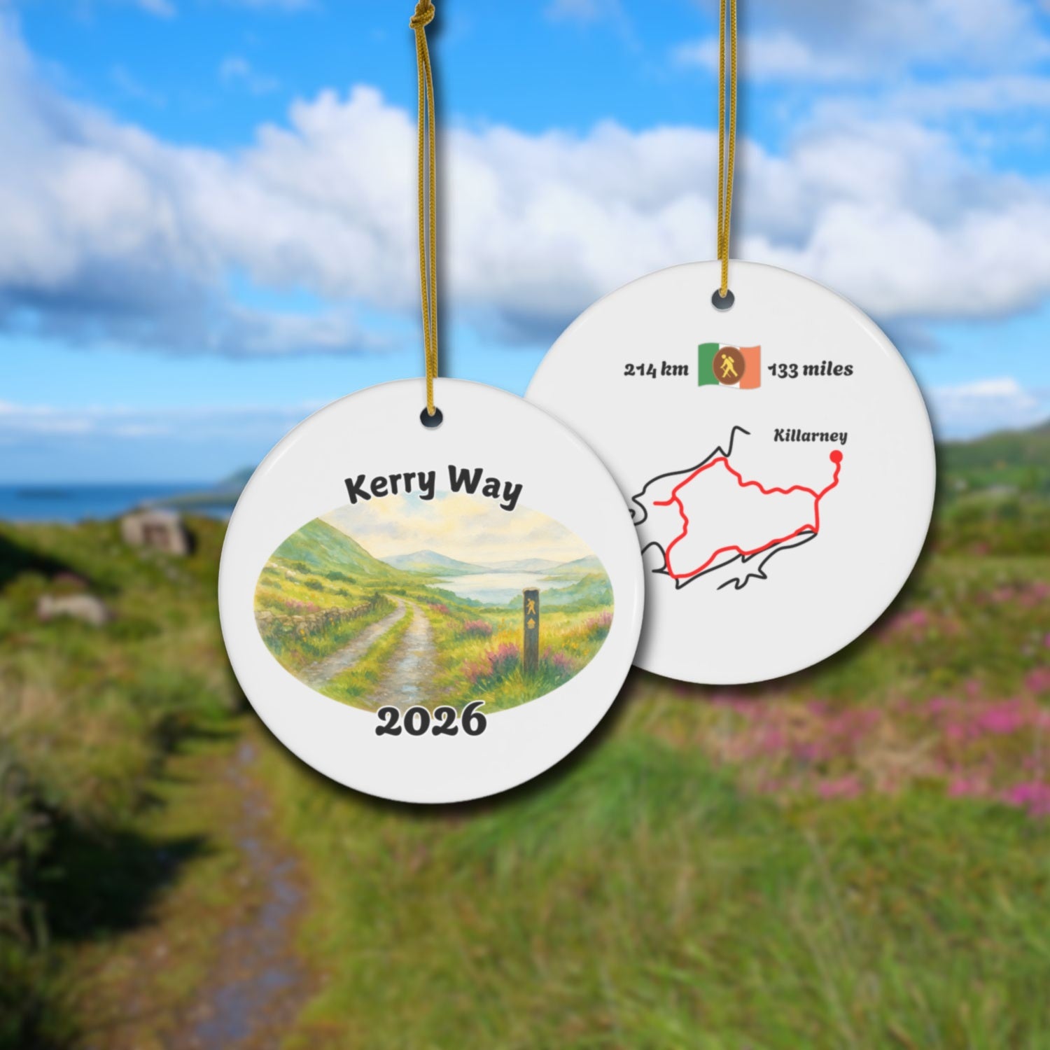 The Kerry Way ceramic ornament with watercolor landscape shown front and back in front of trail landscape.
