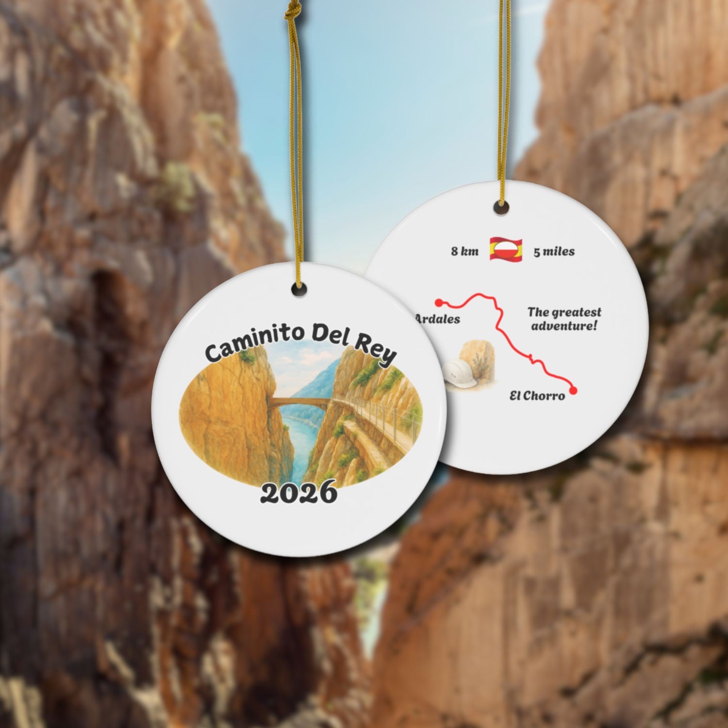 Caminito del Rey ceramic ornament with watercolor landscape shown front and back in front of trail landscape.