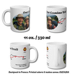 Four views of a 11 oz. white ceramic mug showing a custom printed design of a hiking trail map with a photo of a couple and text reading 'Our Camino Trail'.